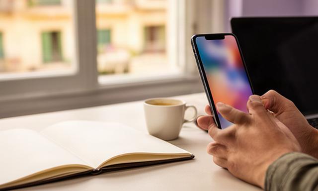Persona usando un teléfono móvil junto a una mesa de trabajo en Barcelona